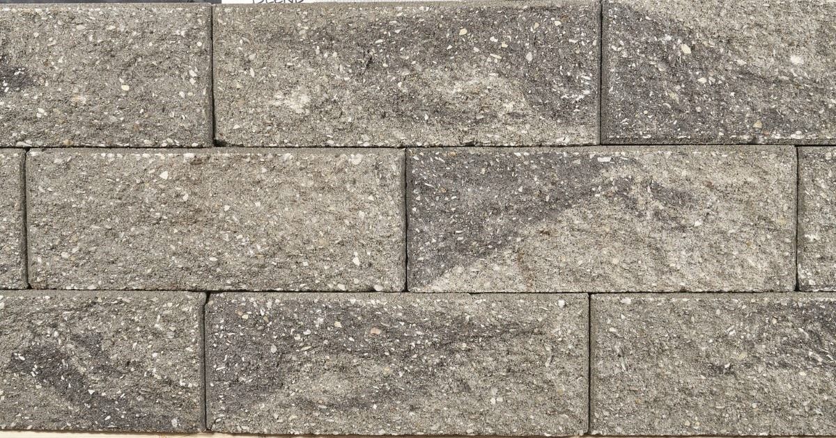 Stacked gray stone retaining wall blocks with visible horizontal and vertical seams.