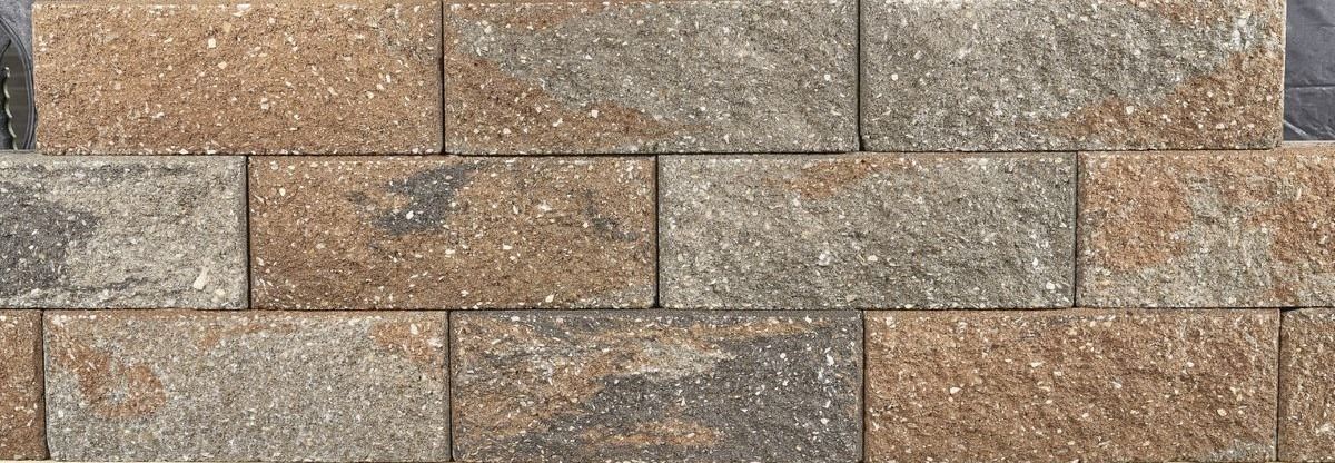 Close-up of a tan and brown brick wall with varied rectangular stones and mortar lines
