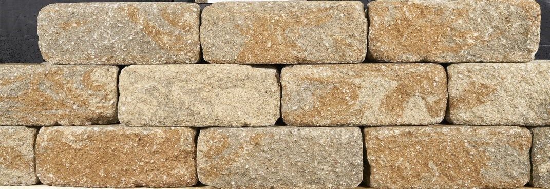 Stacked tan stone bricks with rough textures, arranged in neat horizontal rows.