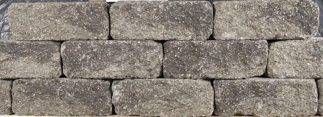 Gray stacked stone wall with rough, weathered bricks