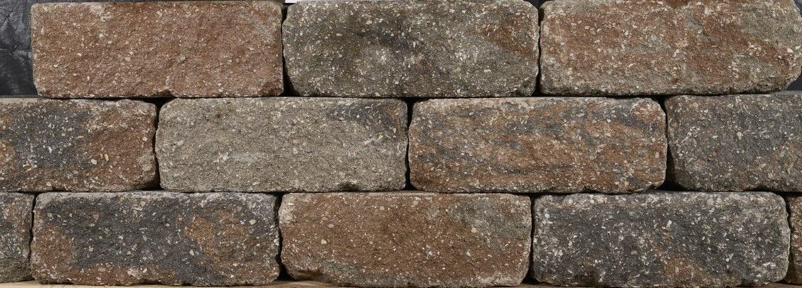 Stacked brown and gray stone wall blocks with rough, weathered texture