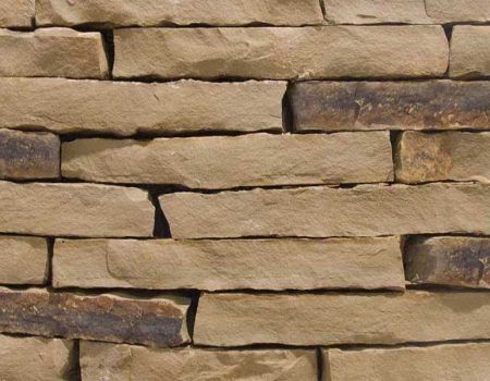 Close-up of stacked tan and brown stone wall with uneven horizontal layers