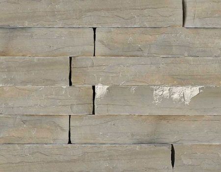 Stacked beige stone tiles with visible horizontal seams and a few dark cracks
