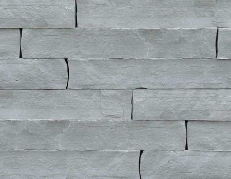 Gray stacked stone wall with staggered rectangular tiles and visible mortar lines