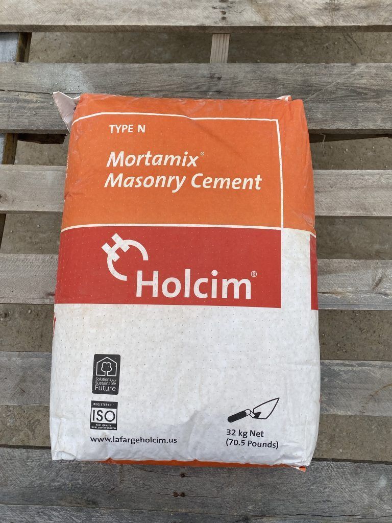 Bag of Holcim Mortamix masonry cement on a wooden pallet, orange and white packaging.