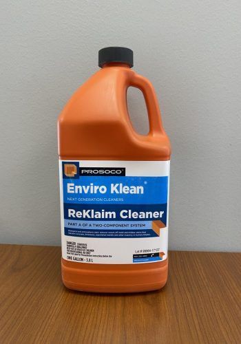 Orange Enviro Klean Reklame Cleaner bottle on a wooden table against a gray wall