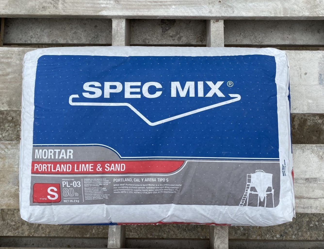 Blue and white SPEC MIX mortar bag labeled Portland Lime & Sand, lying on a pallet.