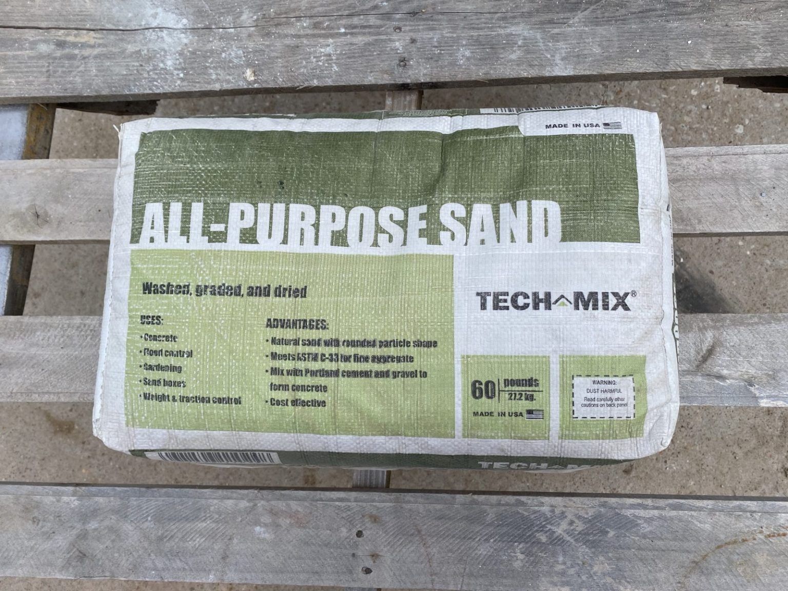 Bag of Tech Mix all-purpose sand on weathered wooden pallets