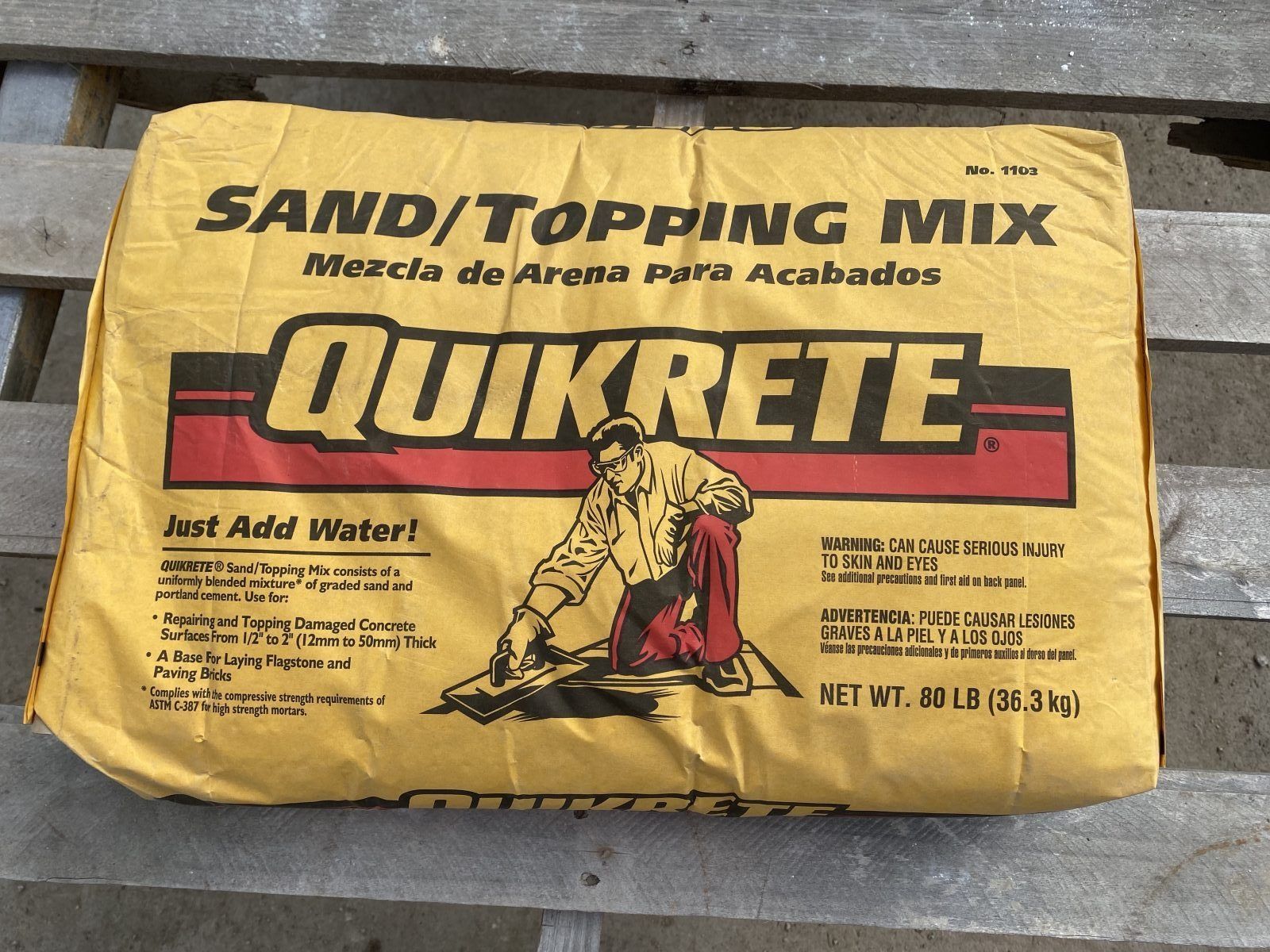 Quikrete sand/topping mix bag, yellow packaging with black and red text on a surface