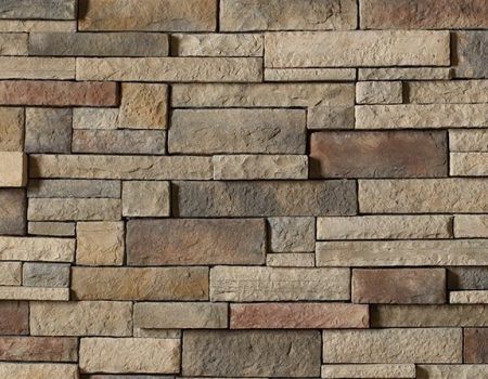 Stacked tan and gray stone wall with staggered rectangular blocks