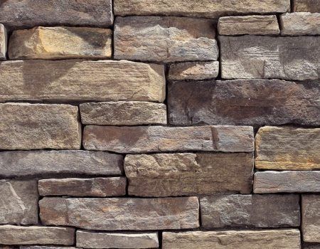 Stacked tan and brown stone wall blocks with rough, textured surfaces.