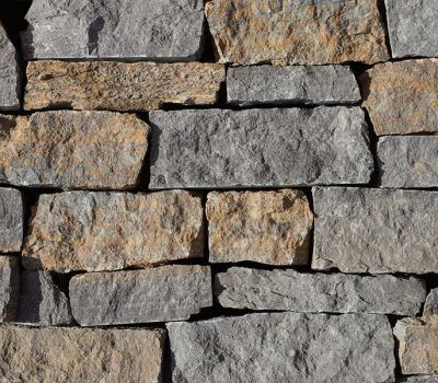 Close-up of a stacked stone wall with rough gray and tan rocks