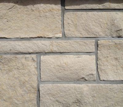 Close-up of a beige stone wall with rectangular masonry blocks and mortar joints
