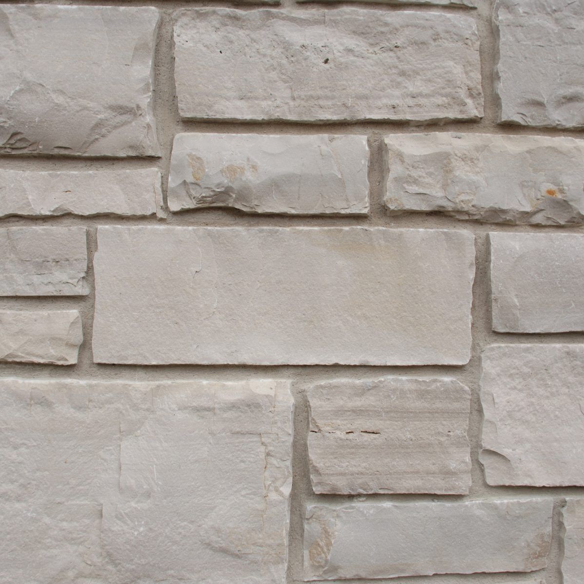 Close-up of a beige stone brick wall with staggered rectangular blocks