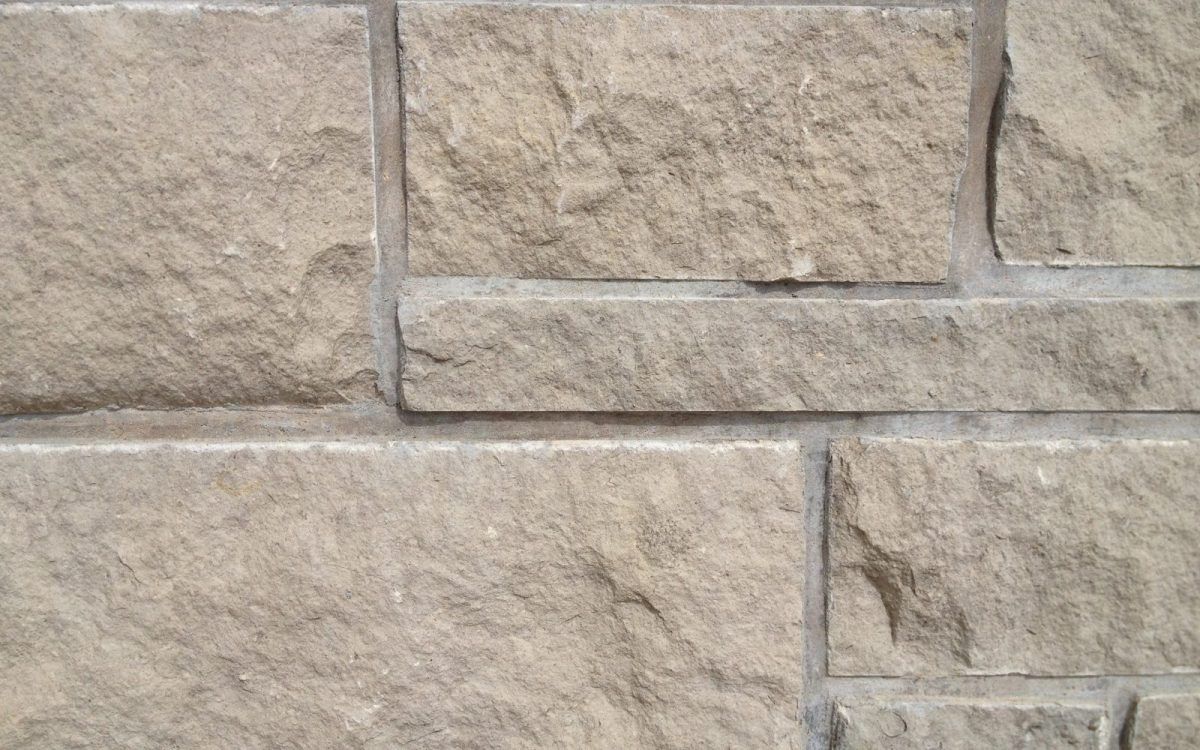 Close-up of beige stone wall with rectangular blocks and mortar lines
