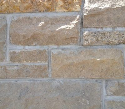 Close-up of tan and gray stone wall blocks with light mortar lines