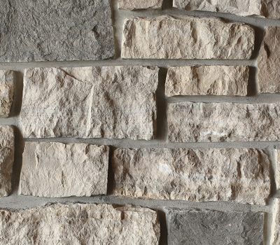 Close-up of a rough gray stone wall with stacked rectangular blocks and mortar joints