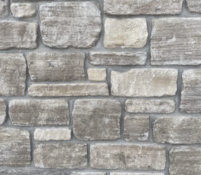 Gray stacked stone wall with rough rectangular blocks and mortar joints