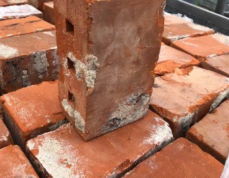 Rusty metal post standing on weathered red bricks with white mortar residue