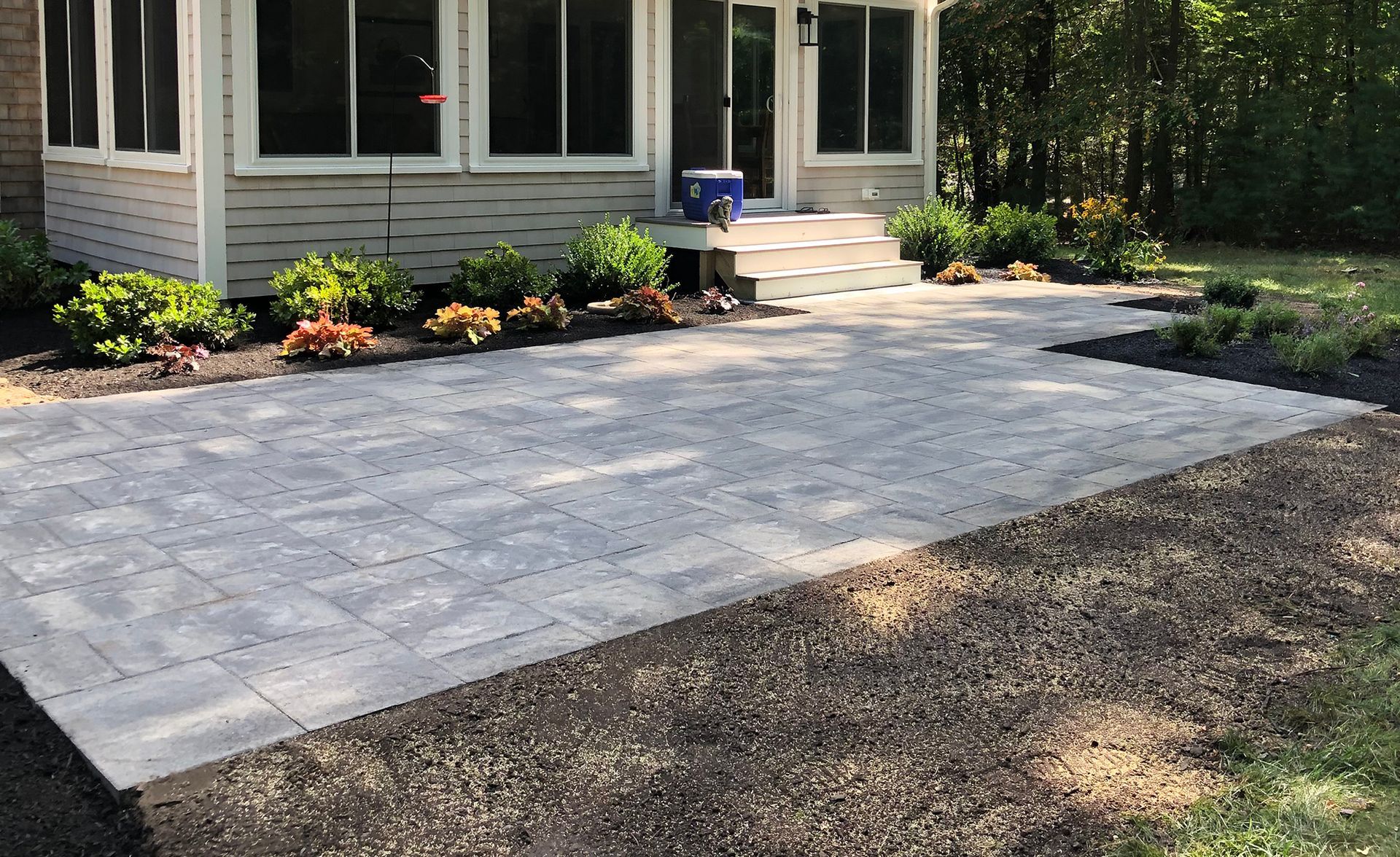A paved driveway with light grey rectangular stones and dark grey border edges, leading toward a house.
