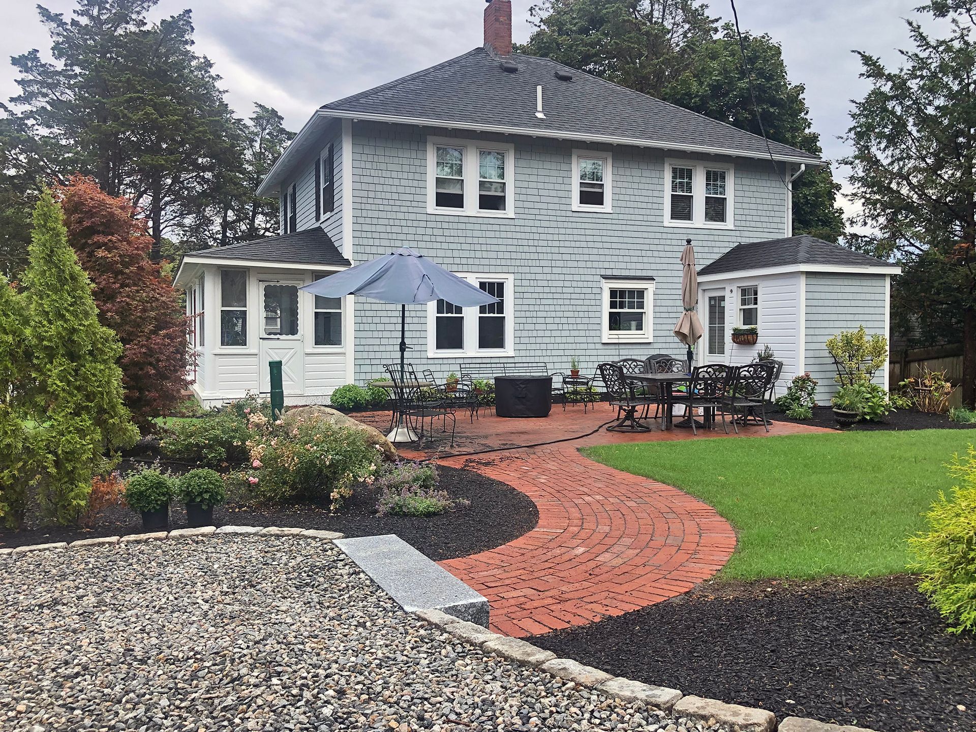 A circular stone patio being constructed within a curved retaining wall in a backyard setting.