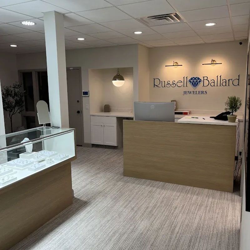 Interior of a jewelry store with display cases, a reception desk, and the store name on the wall.