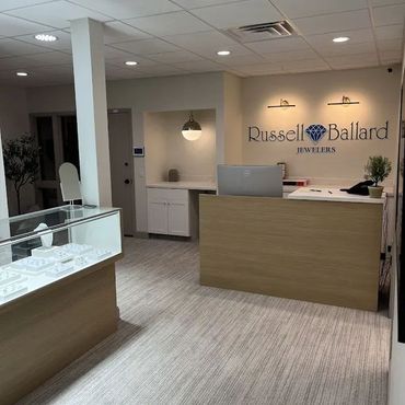 Interior of a jewelry store with display cases, a reception desk, and the store name on the wall.