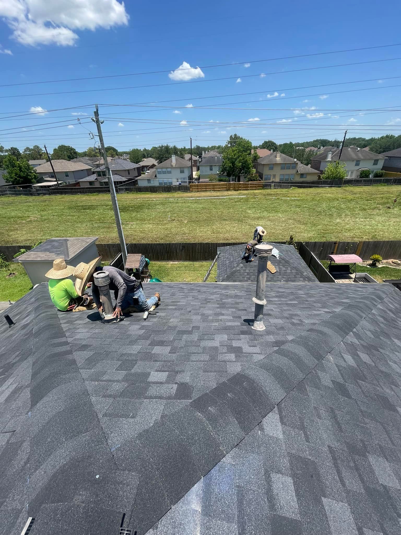 A group of people are working on the roof of a house.