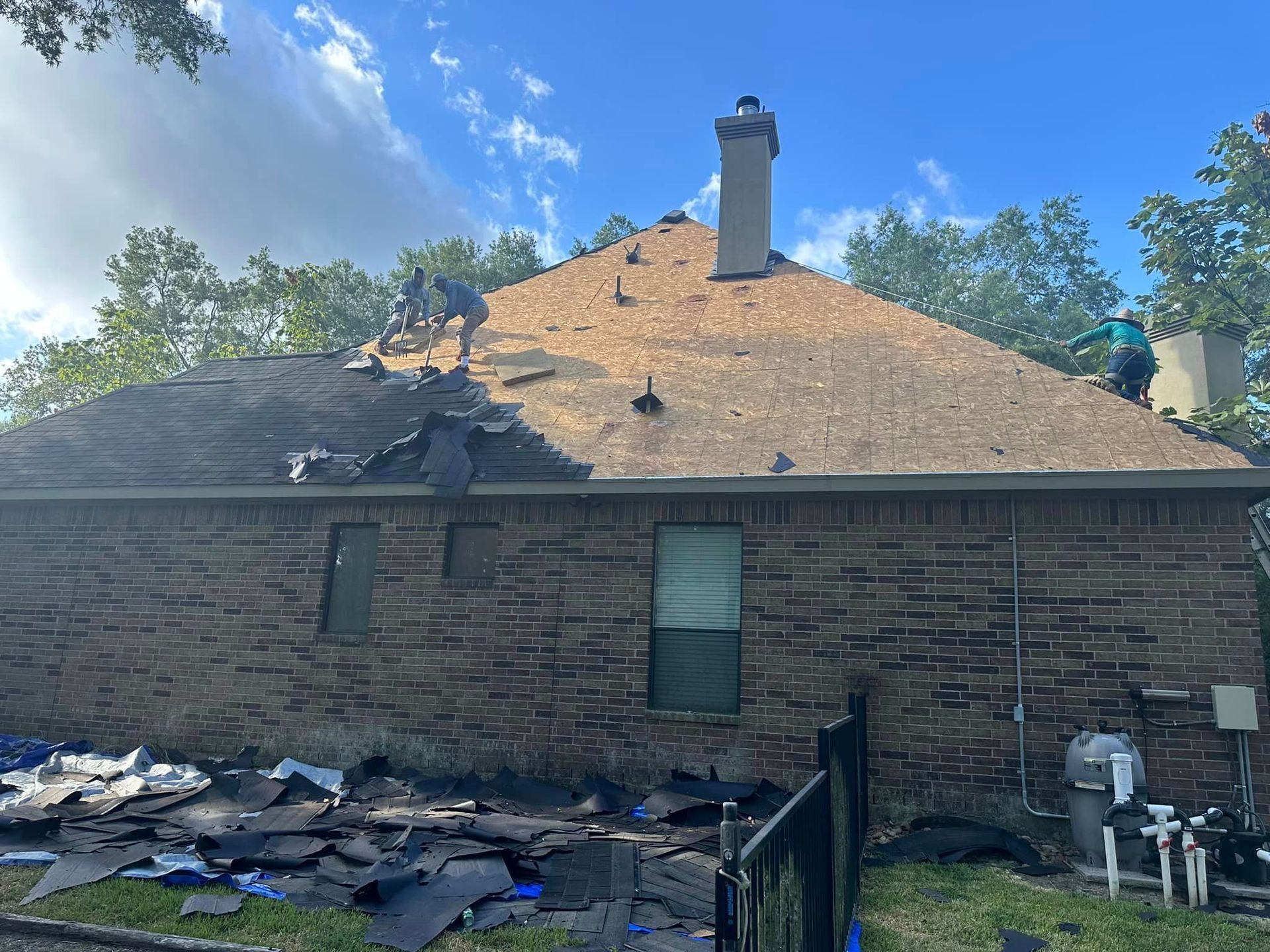A man is working on the roof of a brick house.