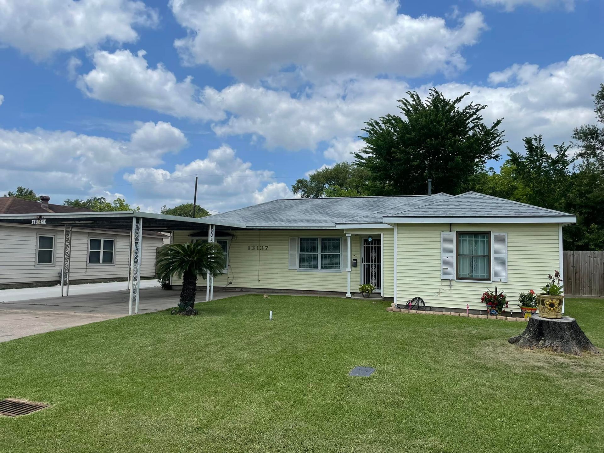 A white house with a blue roof is sitting on top of a lush green lawn.
