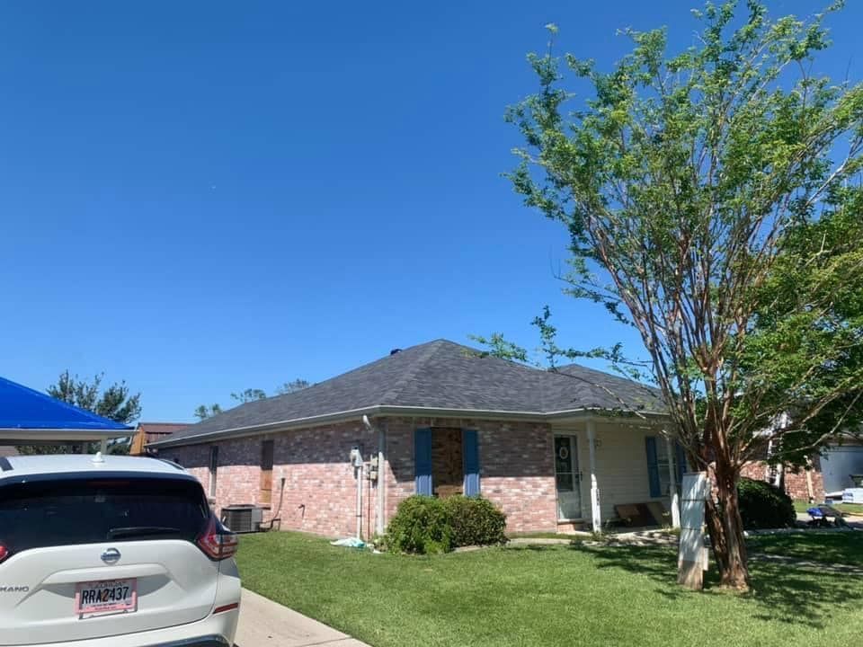 A white car is parked in front of a brick house.
