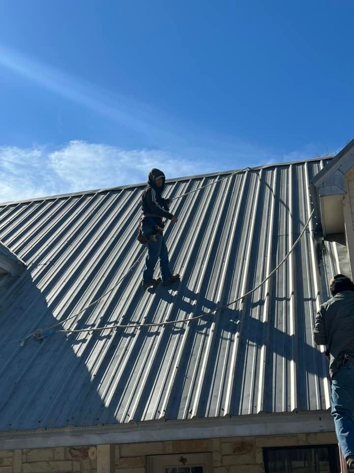 A man is standing on top of a metal roof