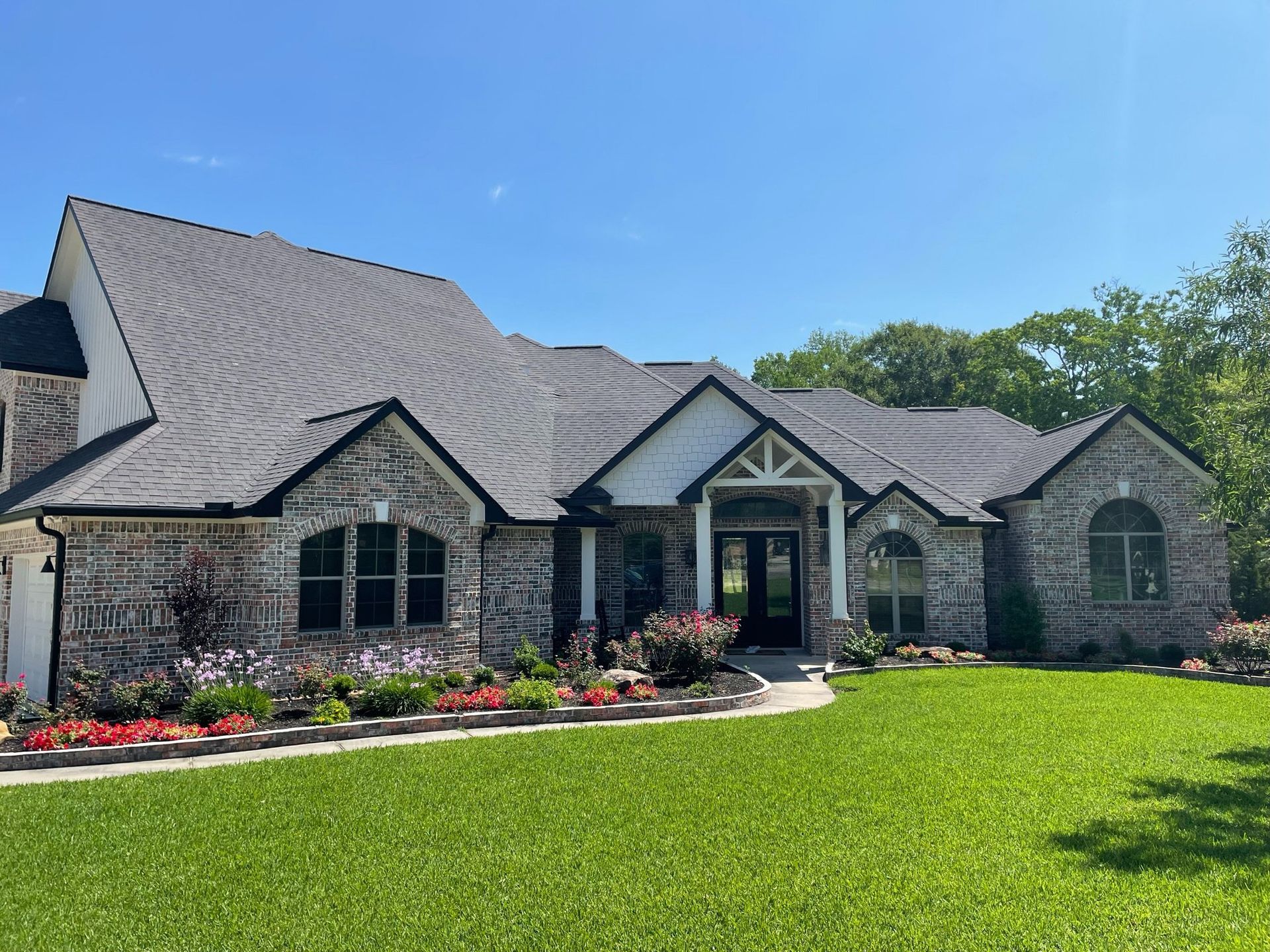 A large brick house with a lush green lawn in front of it.