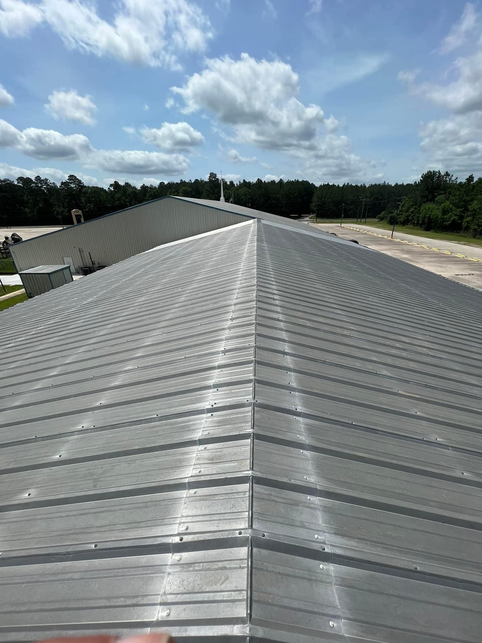 The roof of a building with a blue sky and clouds in the background.