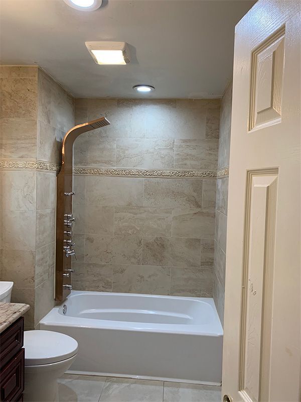 Accessible bathroom with walk-in shower, white tub, beige tile, and grab bar under ceiling lights