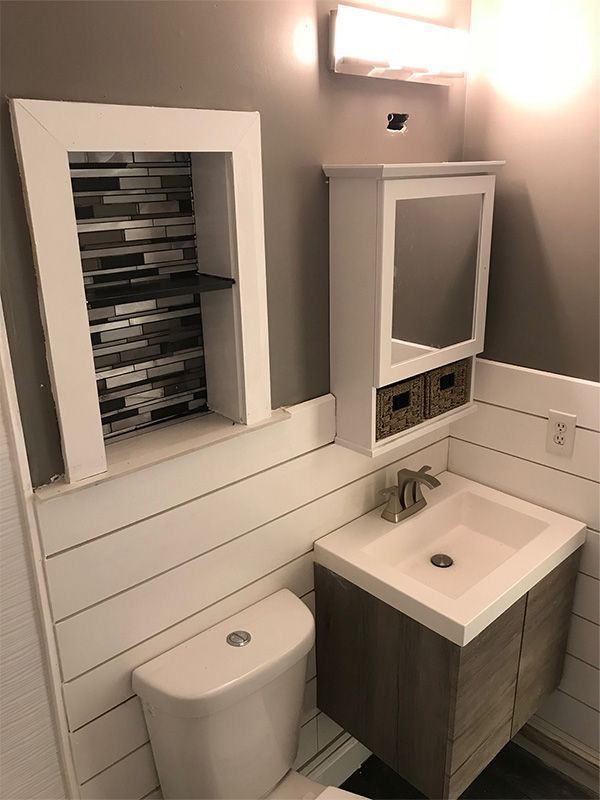 Small bathroom with toilet, sink vanity, wall mirror cabinet, and recessed storage shelf.