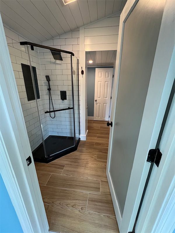 Small hallway with a black pull-up workout station on white tiled walls and wood floors.