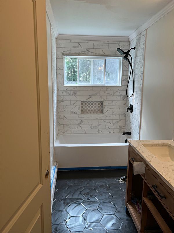 Bathroom with tiled walk-in shower, window, built-in niche, and dark hexagon floor tile