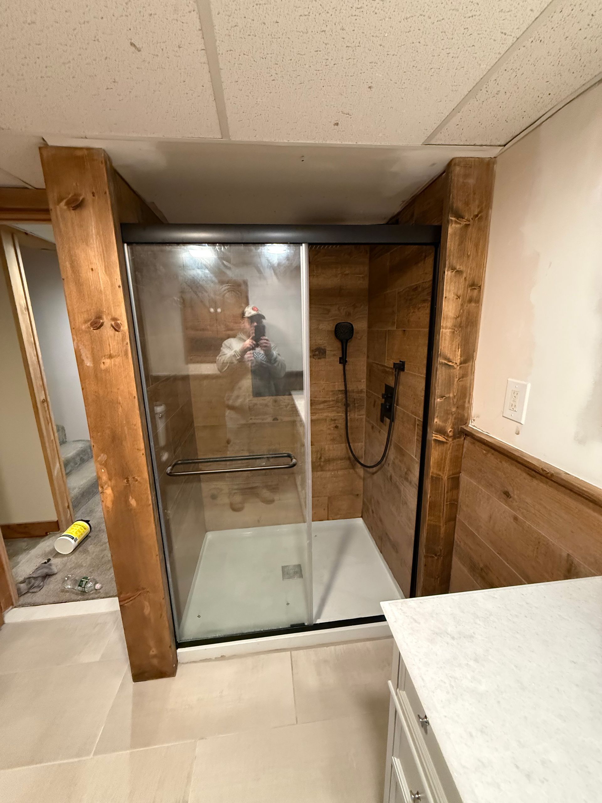 Small bathroom with a glass-enclosed shower, wood trim, and a white vanity in the foreground.