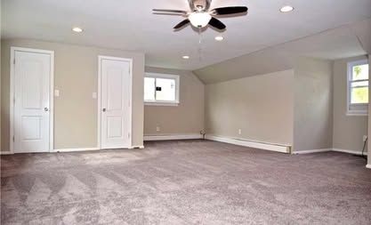 Empty carpeted bedroom with gray walls, white closet doors, ceiling fan, and small windows