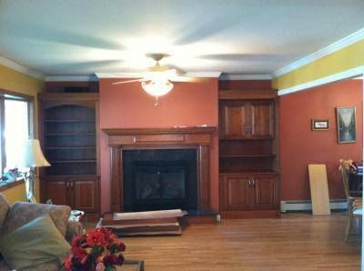 Living room with a fireplace, wood built-ins, yellow walls, and a ceiling fan