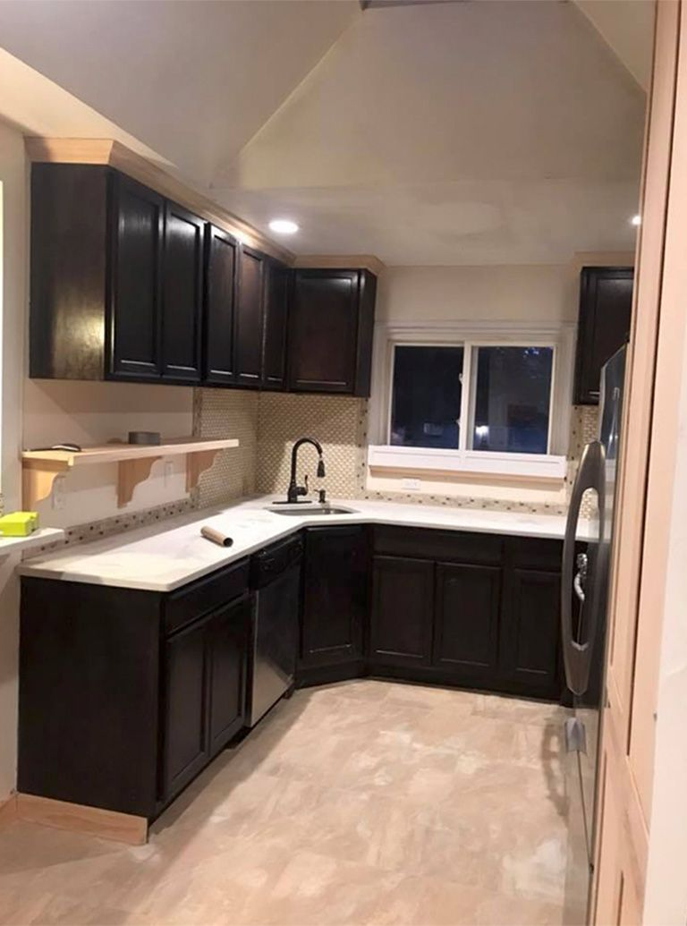Modern kitchen with dark cabinets, white countertops, and a window over the sink