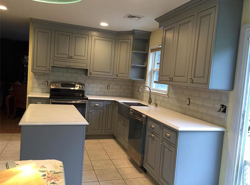 Modern kitchen with gray cabinets, white countertops, tiled floor, and a central island