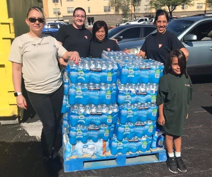 A group of people standing next to a pallet of water