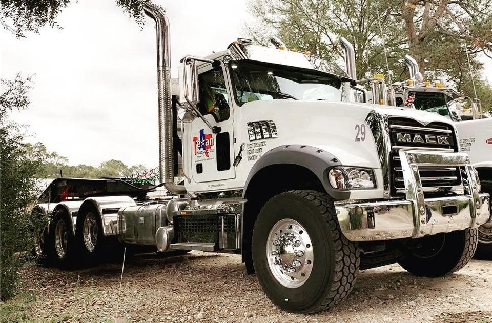 White Mack semi-truck parked outdoors on gravel, viewed from the front-left side.