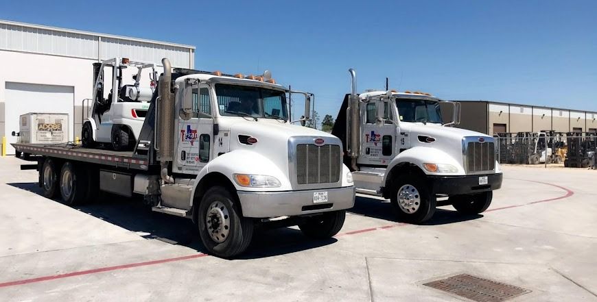Two white freight trucks parked outside a warehouse on a sunny day