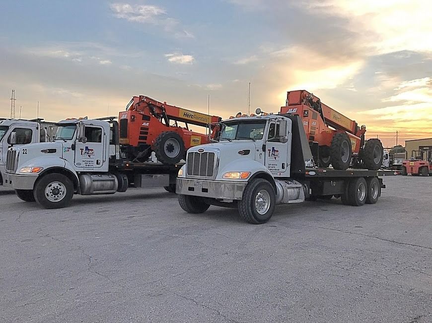 Two white utility trucks with orange cranes parked in a lot at sunset
