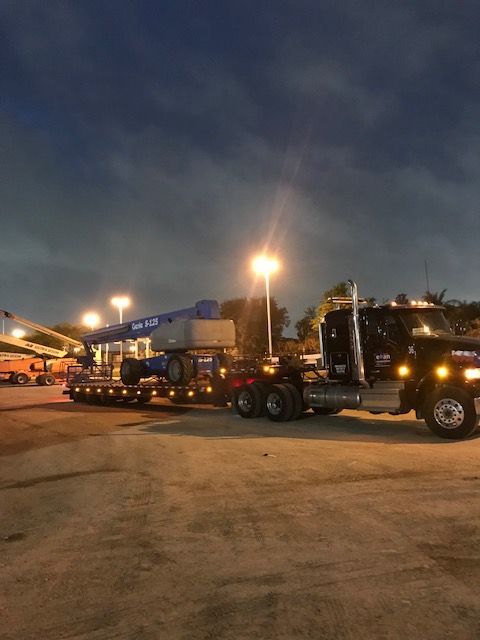 Nighttime truck stop with a line of heavy trucks and bright parking lot lights.