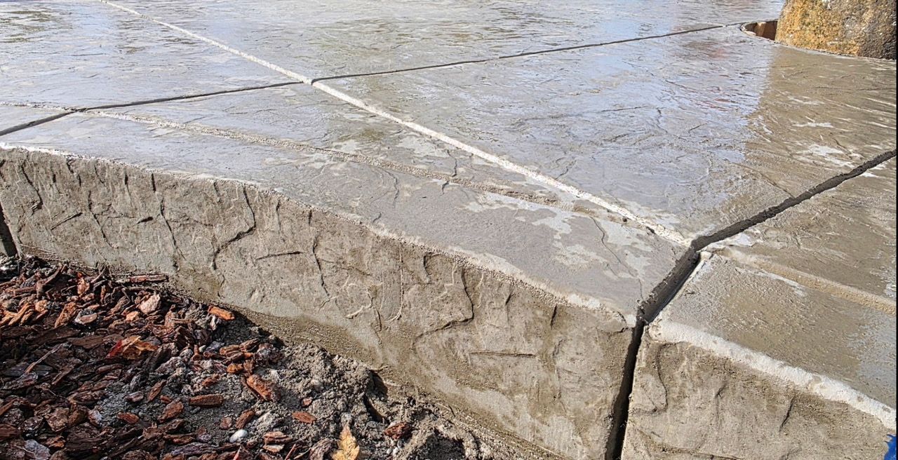 Cracked concrete steps with wet surface and wet leaves along the edge