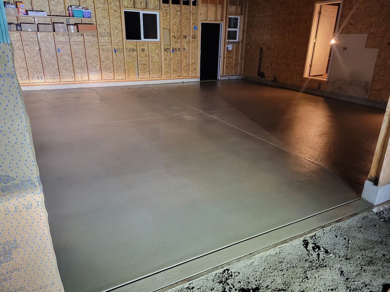 Empty unfinished garage with insulated walls and a smooth concrete floor.